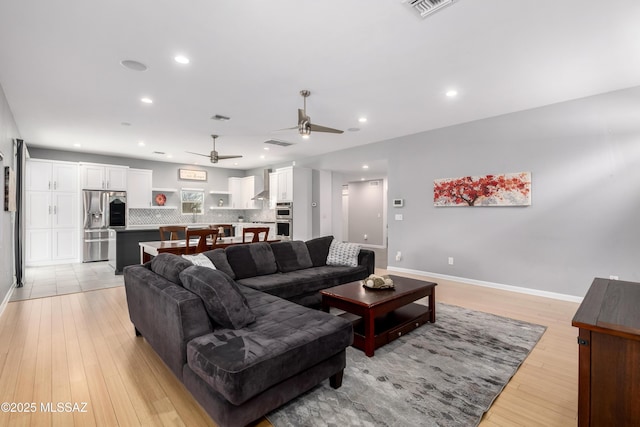 living room with light hardwood / wood-style flooring and ceiling fan