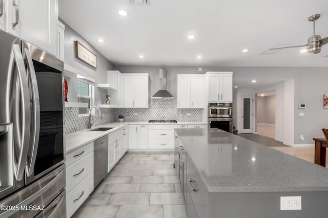 kitchen featuring sink, stainless steel appliances, a center island, white cabinets, and wall chimney exhaust hood