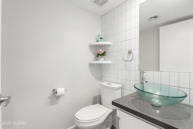 bathroom with tile walls, vanity, decorative backsplash, and toilet