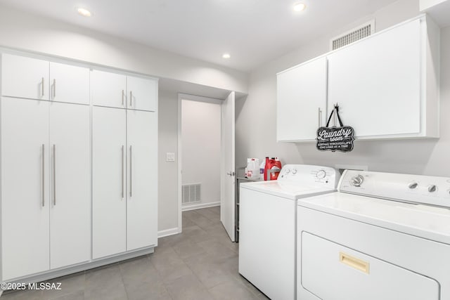 laundry room with cabinets, light tile patterned floors, and washer and dryer