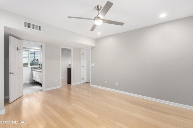 unfurnished bedroom with light hardwood / wood-style flooring, a spacious closet, ceiling fan, ensuite bath, and a closet