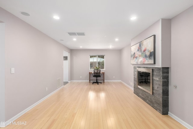 unfurnished living room featuring a tiled fireplace and light hardwood / wood-style floors