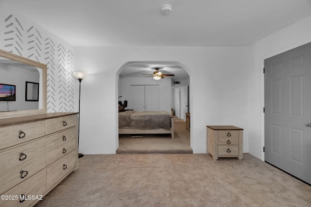 bedroom featuring light colored carpet, ceiling fan, and a closet