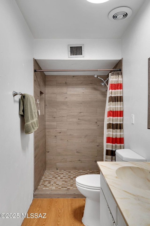 bathroom with wood-type flooring, toilet, vanity, and a shower with curtain