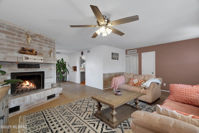 tiled living room featuring a fireplace and ceiling fan