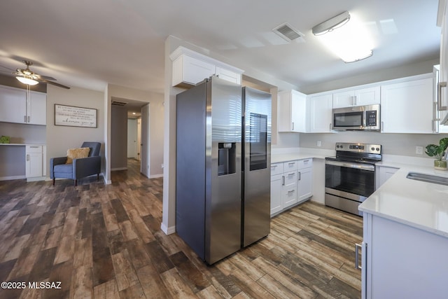 kitchen featuring ceiling fan, dark wood-type flooring, stainless steel appliances, and white cabinetry