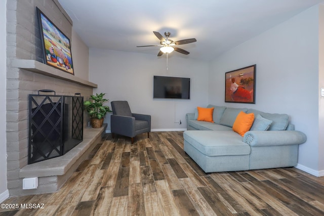 living room with dark hardwood / wood-style flooring, ceiling fan, and a fireplace