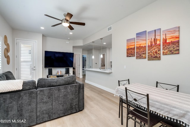 living room with sink, light hardwood / wood-style floors, and ceiling fan