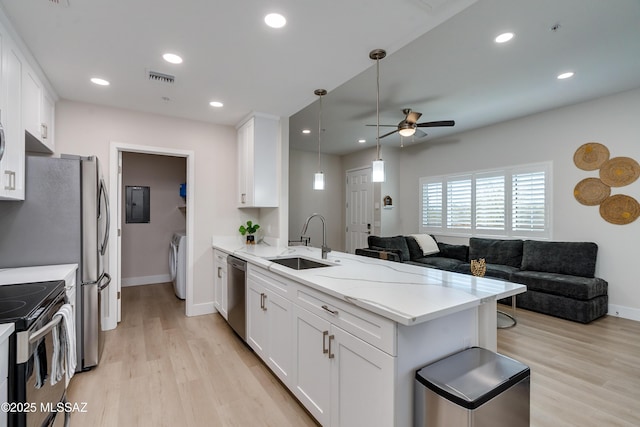 kitchen featuring washer / dryer, appliances with stainless steel finishes, white cabinets, and kitchen peninsula