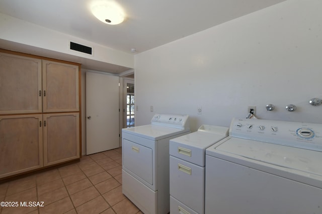 clothes washing area with cabinets, separate washer and dryer, and light tile patterned floors