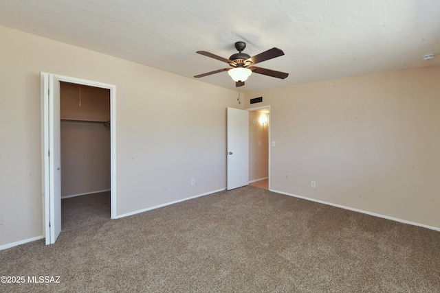 unfurnished bedroom featuring ceiling fan, a spacious closet, carpet floors, and a closet