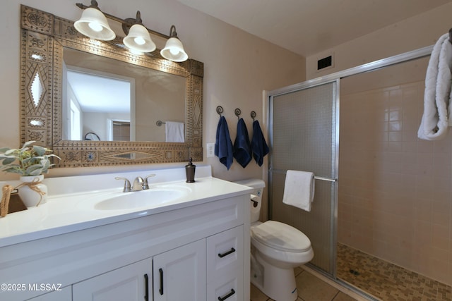 bathroom with toilet, vanity, tile patterned floors, and a shower with shower door