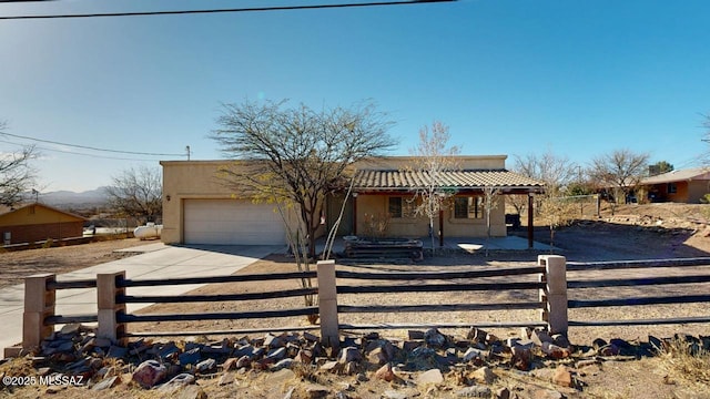 view of front of property featuring a fenced front yard, covered porch, concrete driveway, a tiled roof, and stucco siding