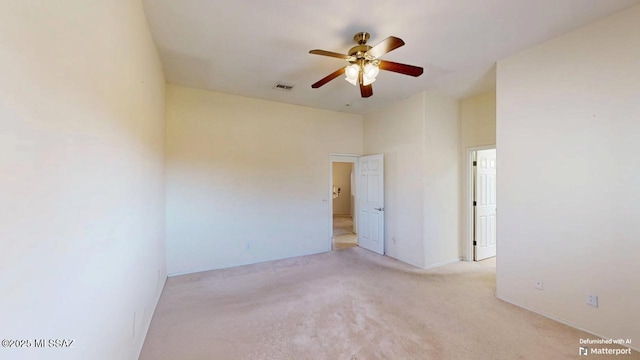 spare room featuring light carpet, visible vents, and a ceiling fan