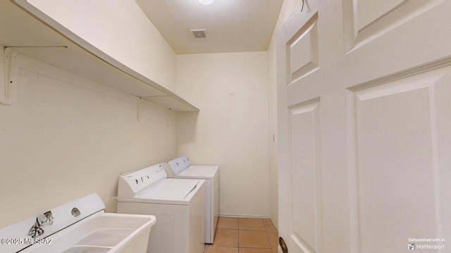 washroom with light tile patterned floors, laundry area, and washer and clothes dryer