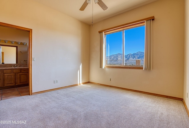 empty room featuring a mountain view, sink, light carpet, and ceiling fan