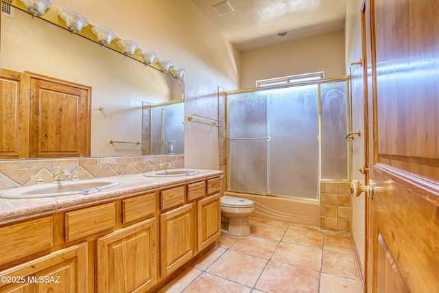 full bathroom featuring enclosed tub / shower combo, vanity, decorative backsplash, tile patterned floors, and toilet