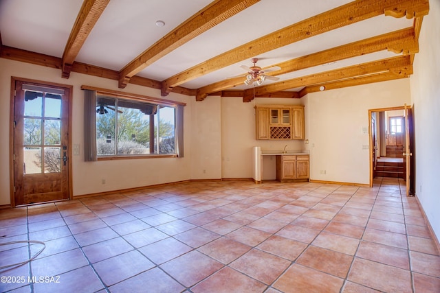 unfurnished living room featuring light tile patterned flooring, ceiling fan, indoor wet bar, and beamed ceiling