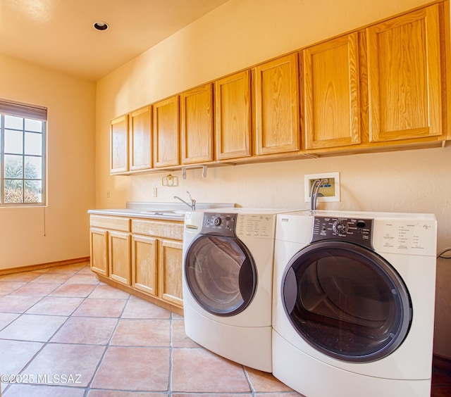 laundry room with light tile patterned flooring, cabinets, sink, and washing machine and clothes dryer