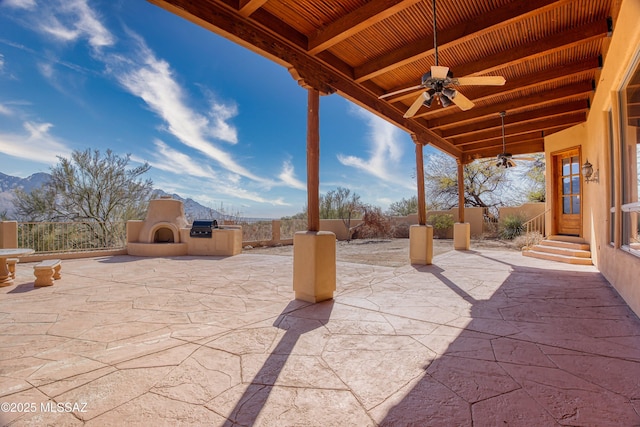 view of patio featuring ceiling fan, a large fireplace, and a mountain view