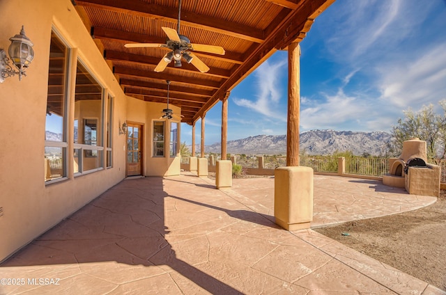 view of patio / terrace with exterior fireplace, a mountain view, and ceiling fan