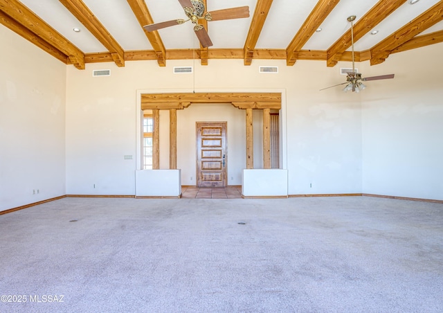 carpeted spare room featuring beamed ceiling and ceiling fan