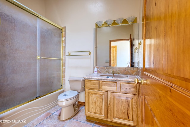 full bathroom featuring combined bath / shower with glass door, tasteful backsplash, vanity, toilet, and tile patterned floors