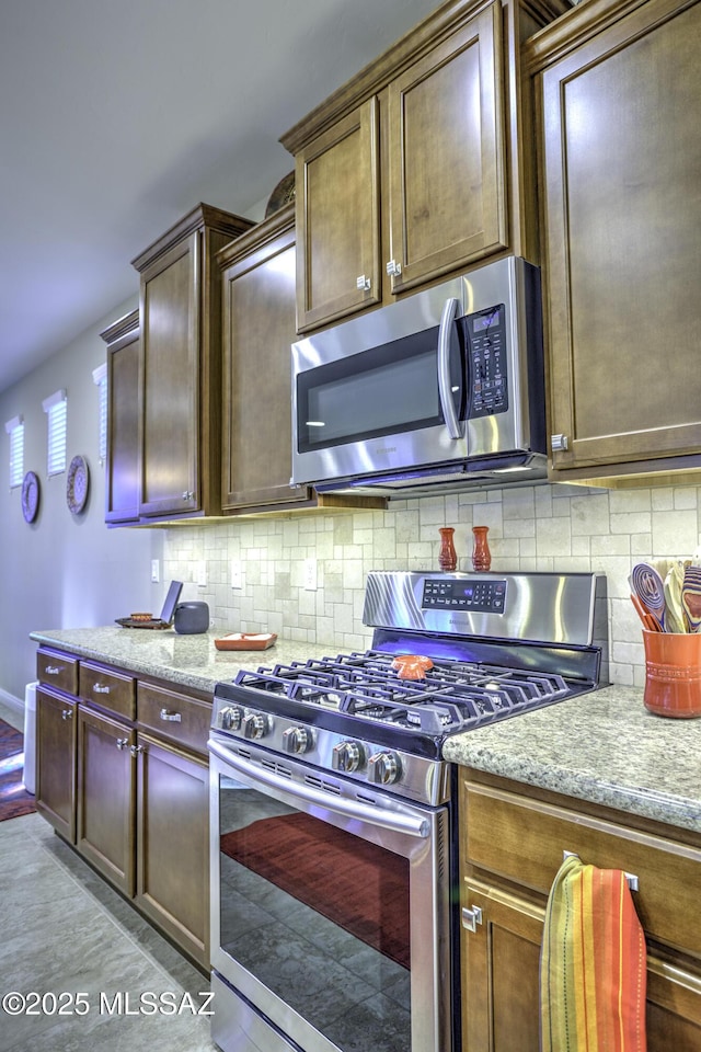 kitchen featuring light stone counters, backsplash, and appliances with stainless steel finishes