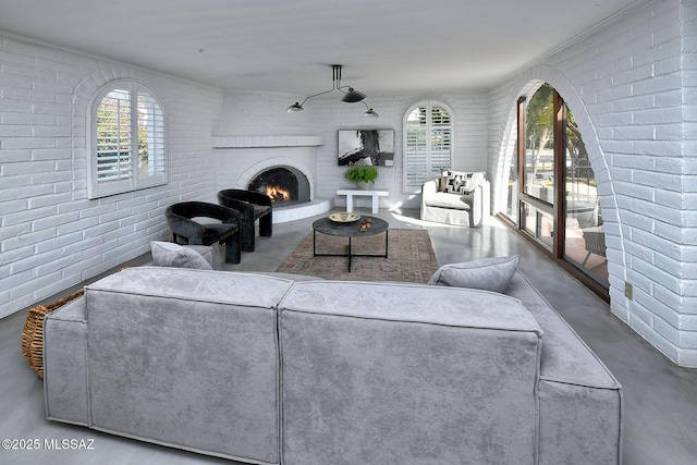 living room with a brick fireplace, concrete floors, and brick wall