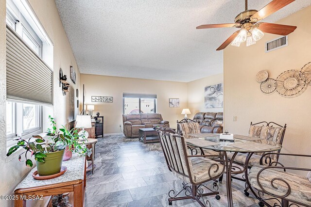 dining area with ceiling fan and a textured ceiling