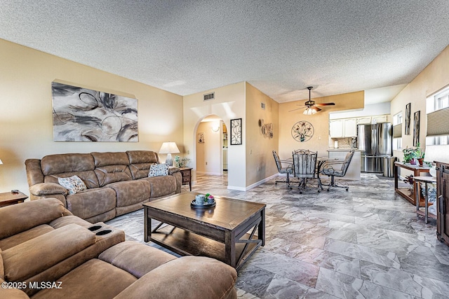 living room with a textured ceiling and ceiling fan