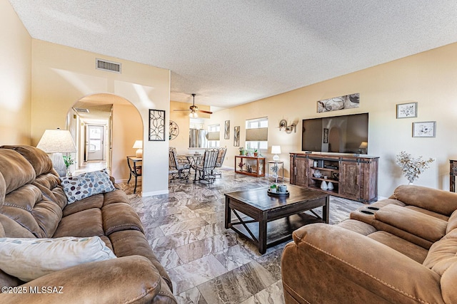 living room featuring ceiling fan and a textured ceiling