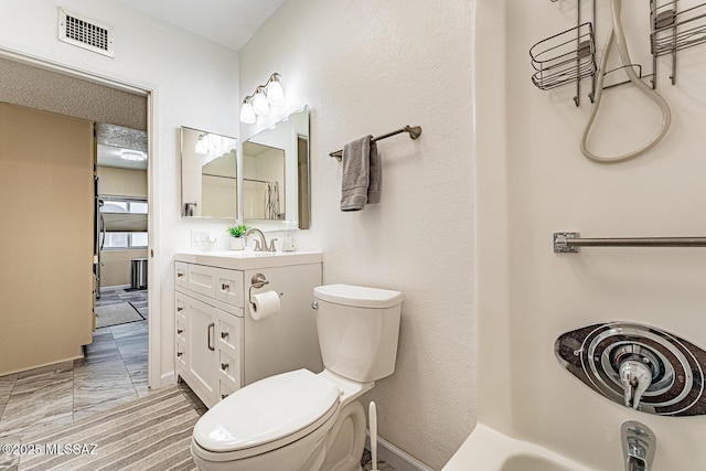 bathroom with walk in shower, vanity, and toilet