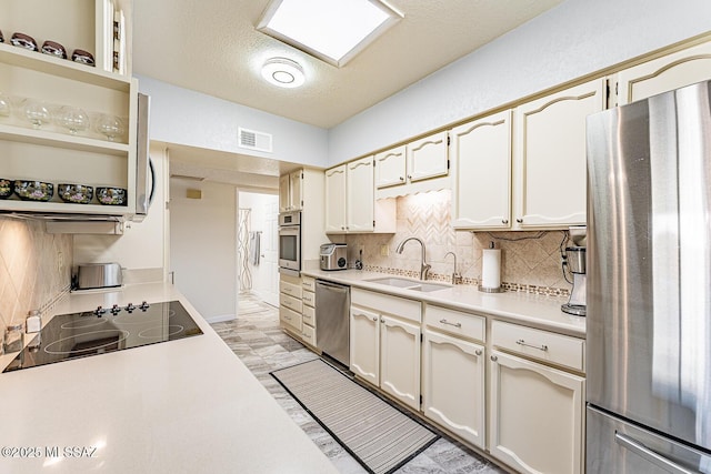 kitchen featuring stainless steel appliances, sink, a textured ceiling, and backsplash