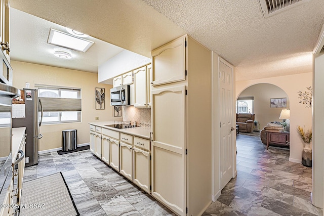 kitchen with tasteful backsplash, a healthy amount of sunlight, black electric stovetop, and a skylight