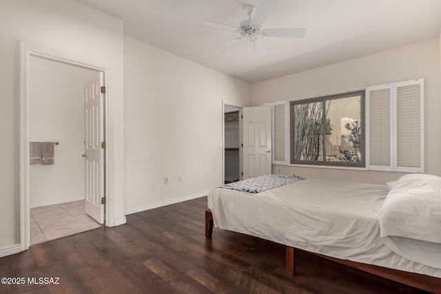 bedroom with a walk in closet, dark wood-type flooring, and ceiling fan