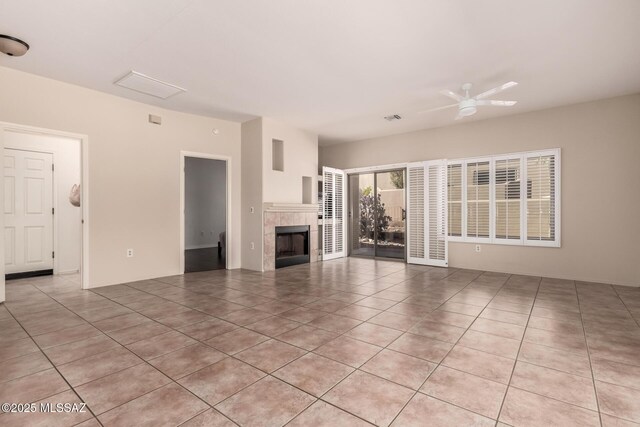 unfurnished living room with light tile patterned flooring, ceiling fan, and a fireplace