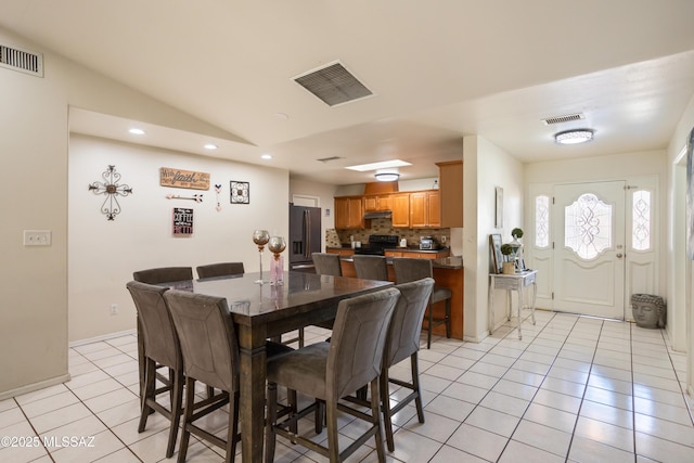 dining room featuring lofted ceiling and light tile patterned floors