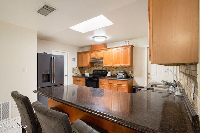 kitchen featuring sink, a skylight, stainless steel fridge with ice dispenser, black range with electric cooktop, and backsplash