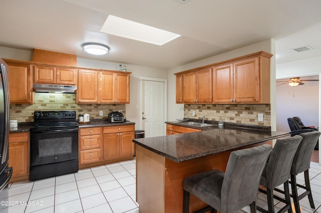 kitchen with light tile patterned flooring, a kitchen breakfast bar, kitchen peninsula, and black electric range