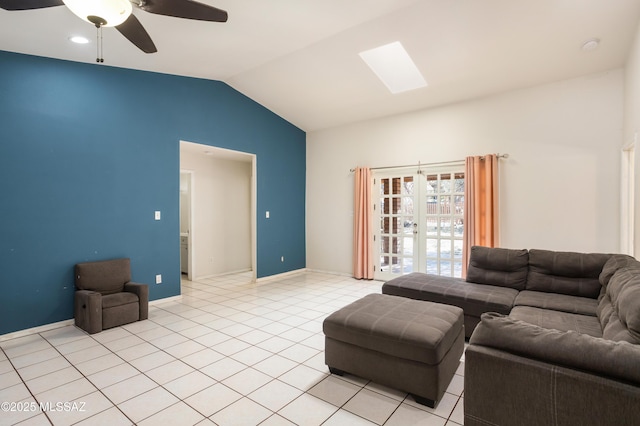 living room with ceiling fan, vaulted ceiling with skylight, and light tile patterned floors