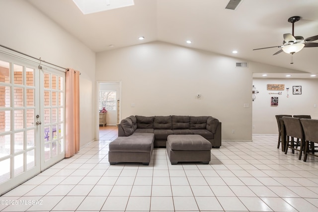 living room with vaulted ceiling with skylight, light tile patterned floors, ceiling fan, and french doors