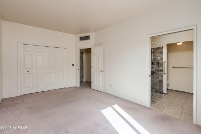 unfurnished bedroom with ensuite bathroom, light colored carpet, and a closet