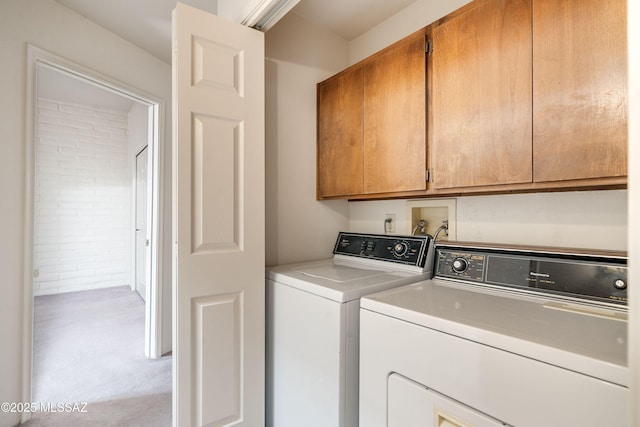 laundry room with separate washer and dryer, light carpet, and cabinets