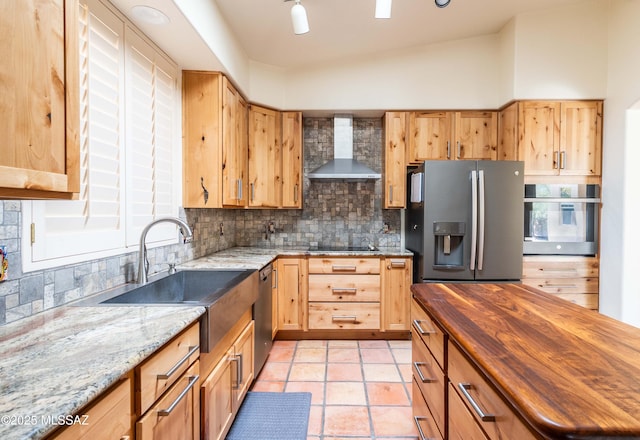 kitchen with wood counters, decorative backsplash, stainless steel appliances, and wall chimney exhaust hood