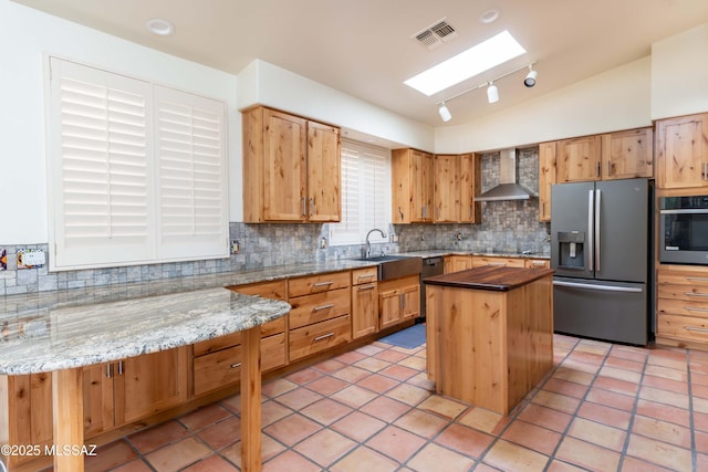 kitchen featuring tasteful backsplash, sink, a center island, black appliances, and wall chimney range hood