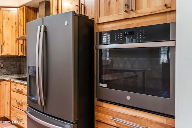 kitchen with tasteful backsplash, appliances with stainless steel finishes, and light stone counters