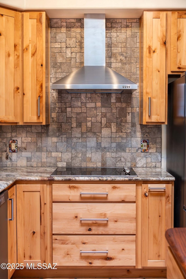 kitchen with dark stone countertops, backsplash, black appliances, and wall chimney exhaust hood