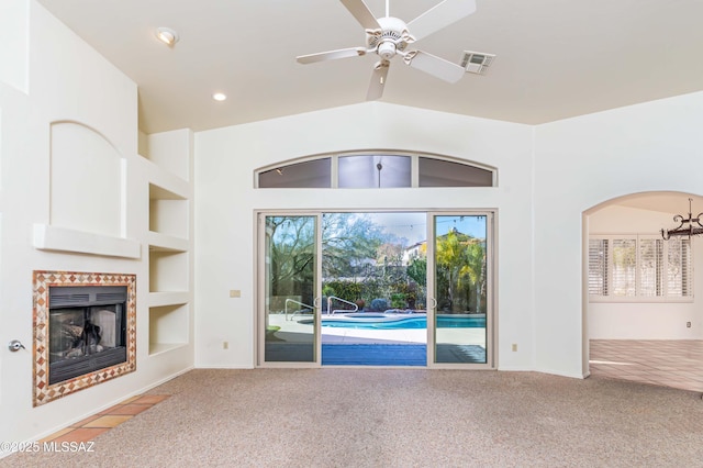 unfurnished living room with built in shelves, light colored carpet, and a wealth of natural light