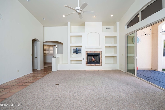 unfurnished living room featuring carpet floors, built in features, a tile fireplace, and ceiling fan